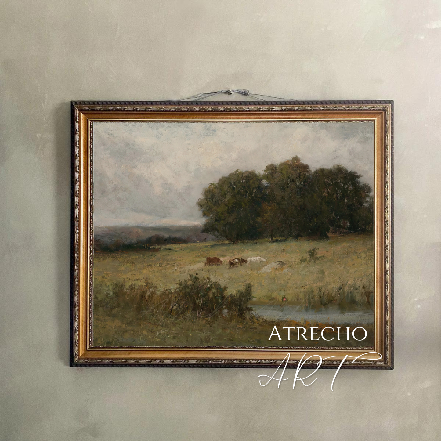 Vintage countryside landscape print hung on a warm plaster wall — pastoral cattle scene displayed with cord, moody old world aesthetic